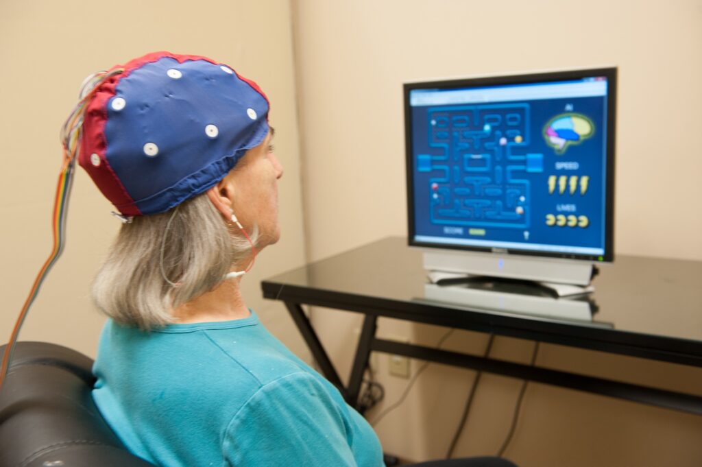 Mujer utilizando una banda de neurofeedback en la cabeza mientras observa en la pantalla un ejercicio tipo laberinto para entrenar su actividad cerebral.